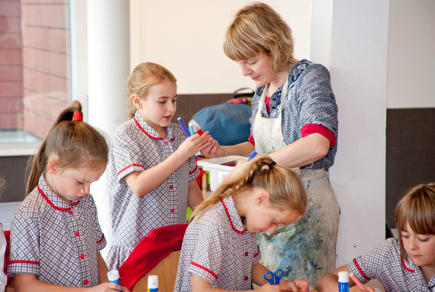 Children in school uniform working with an artist